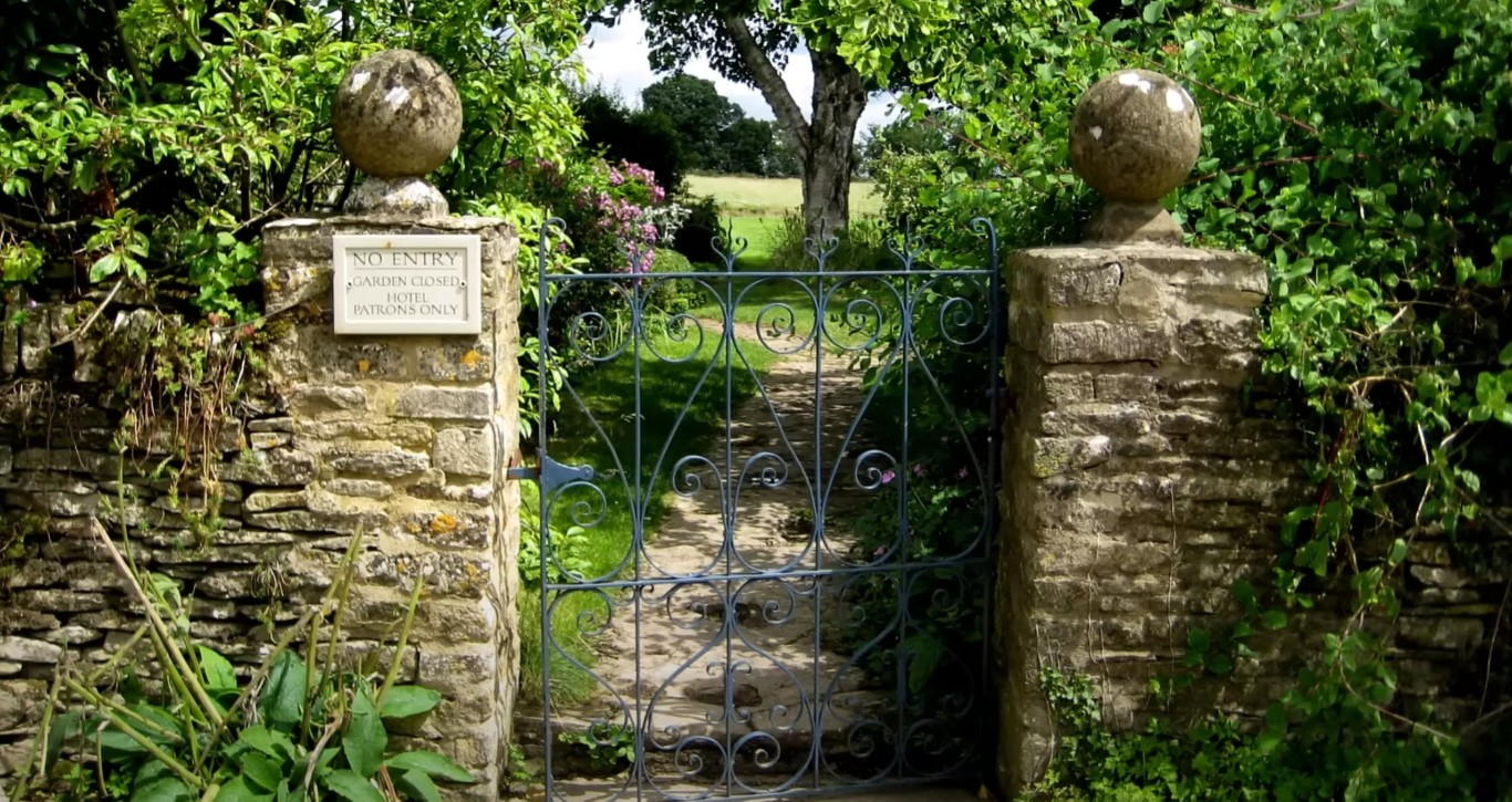 Healthy trees and shrubs surrounding ornate garden gate in Passaic, NJ